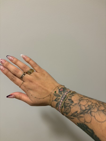 Tattooed hand with bracelets and jewelry.