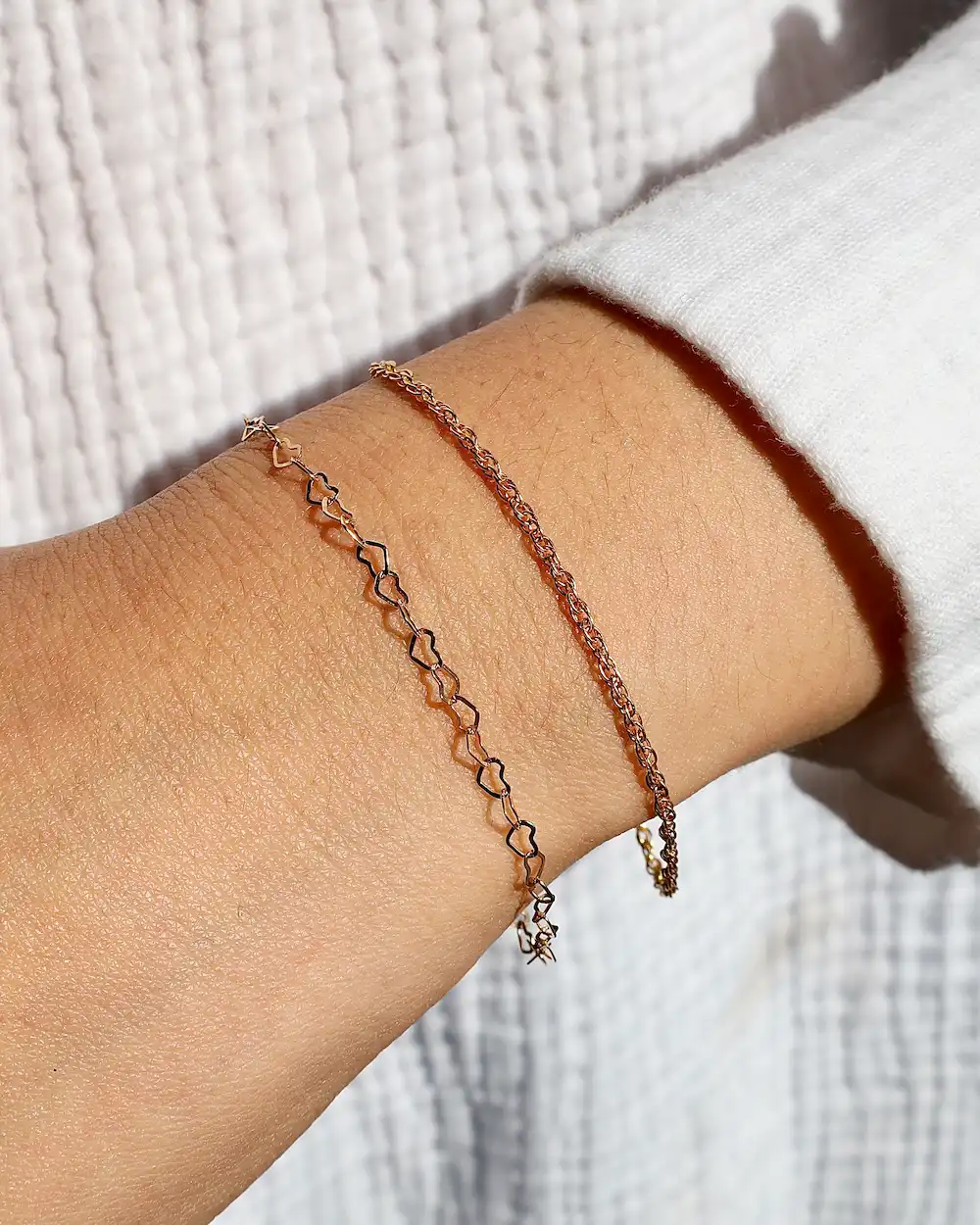 Two delicate gold chain bracelets on wrist