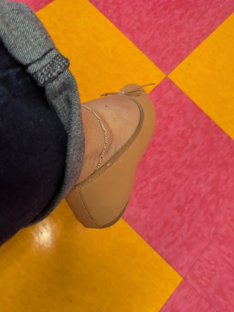 Foot with anklet on colorful tiled floor
