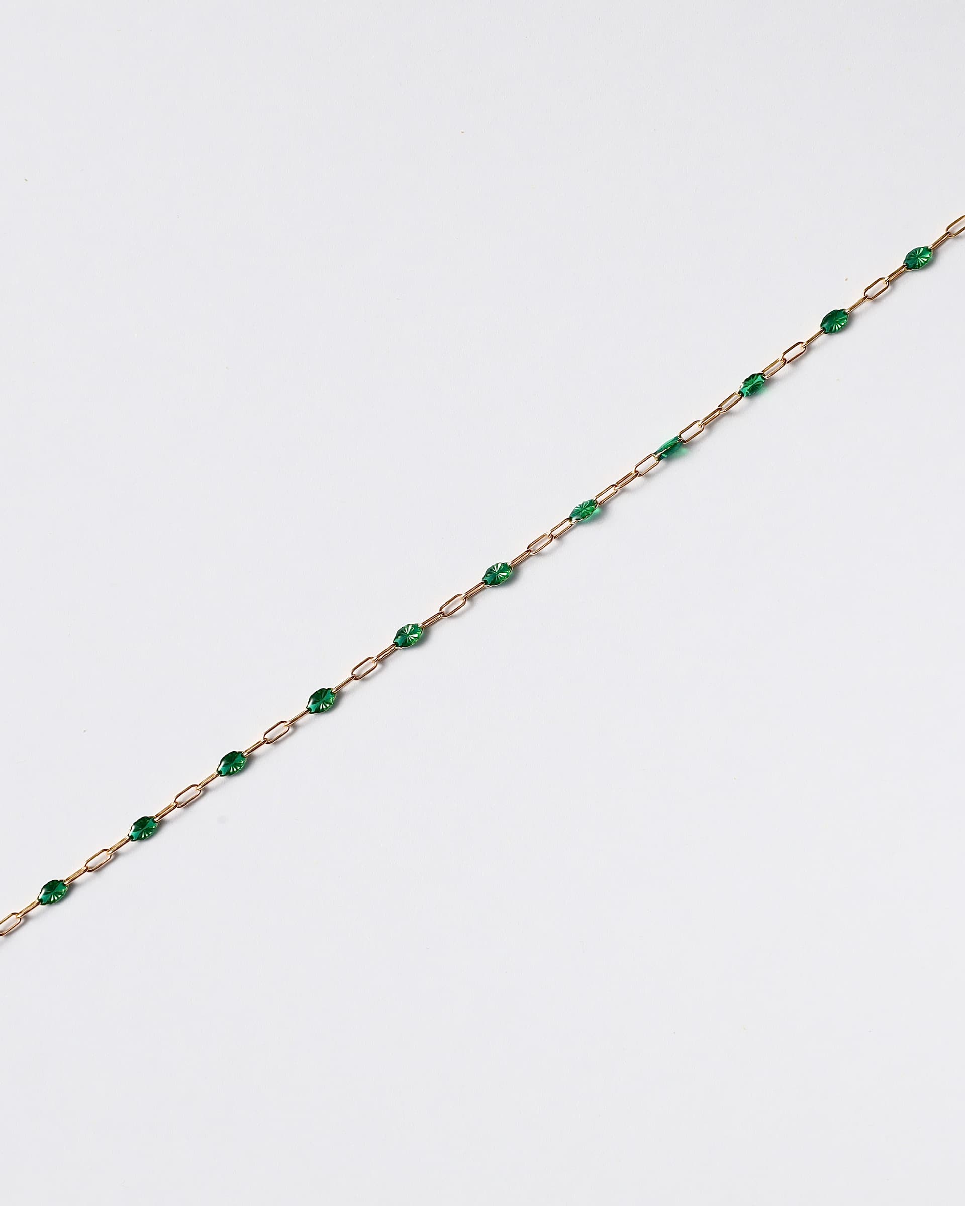 Gold chain with green beads on white background.