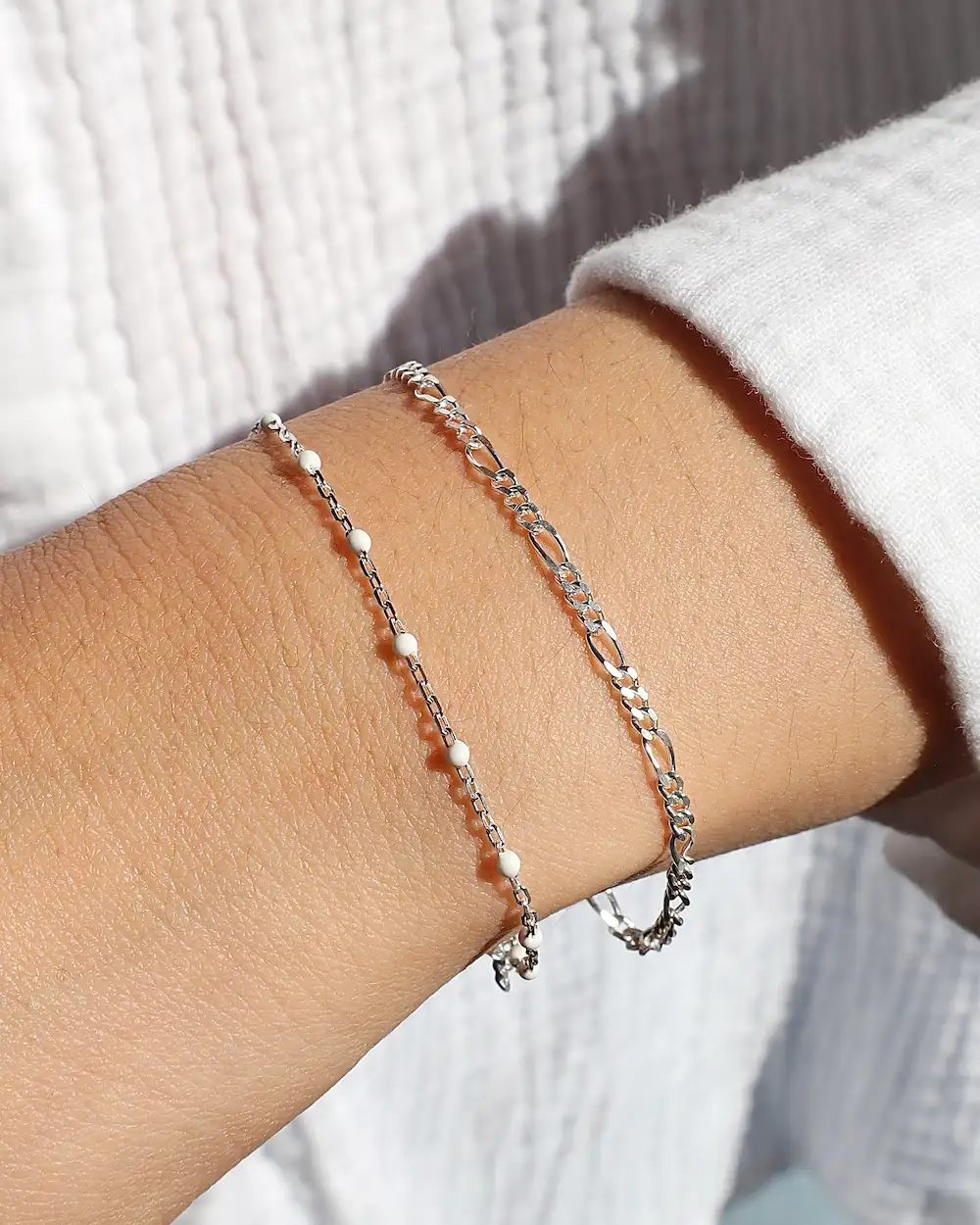Two delicate silver bracelets on wrist