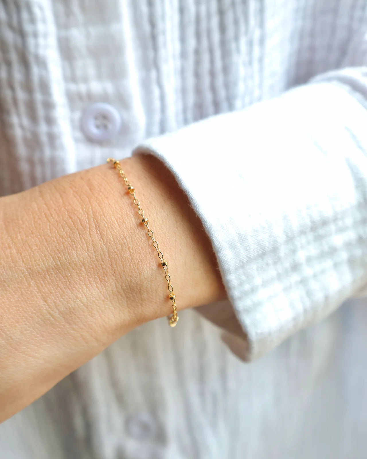 Gold bracelet on wrist with white shirt