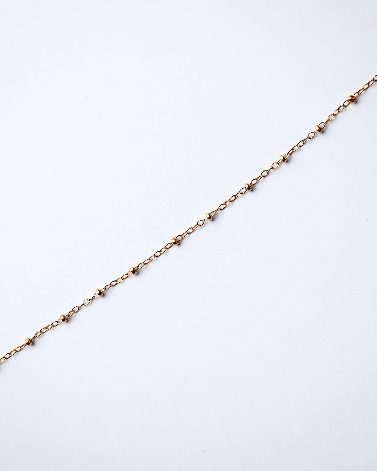 Delicate gold chain on white background